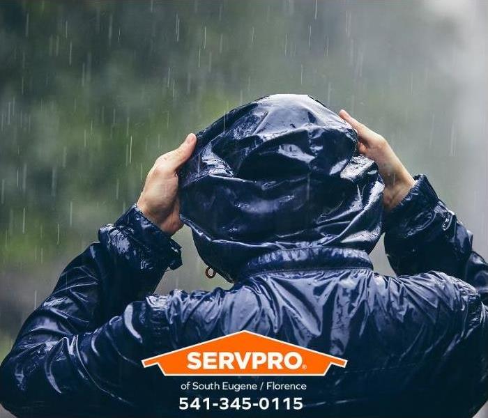 A person wearing rain gear stands outside in a rainstorm.